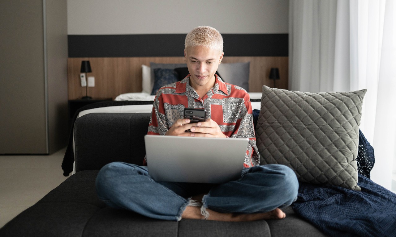 Young man using smartphone and laptop at home