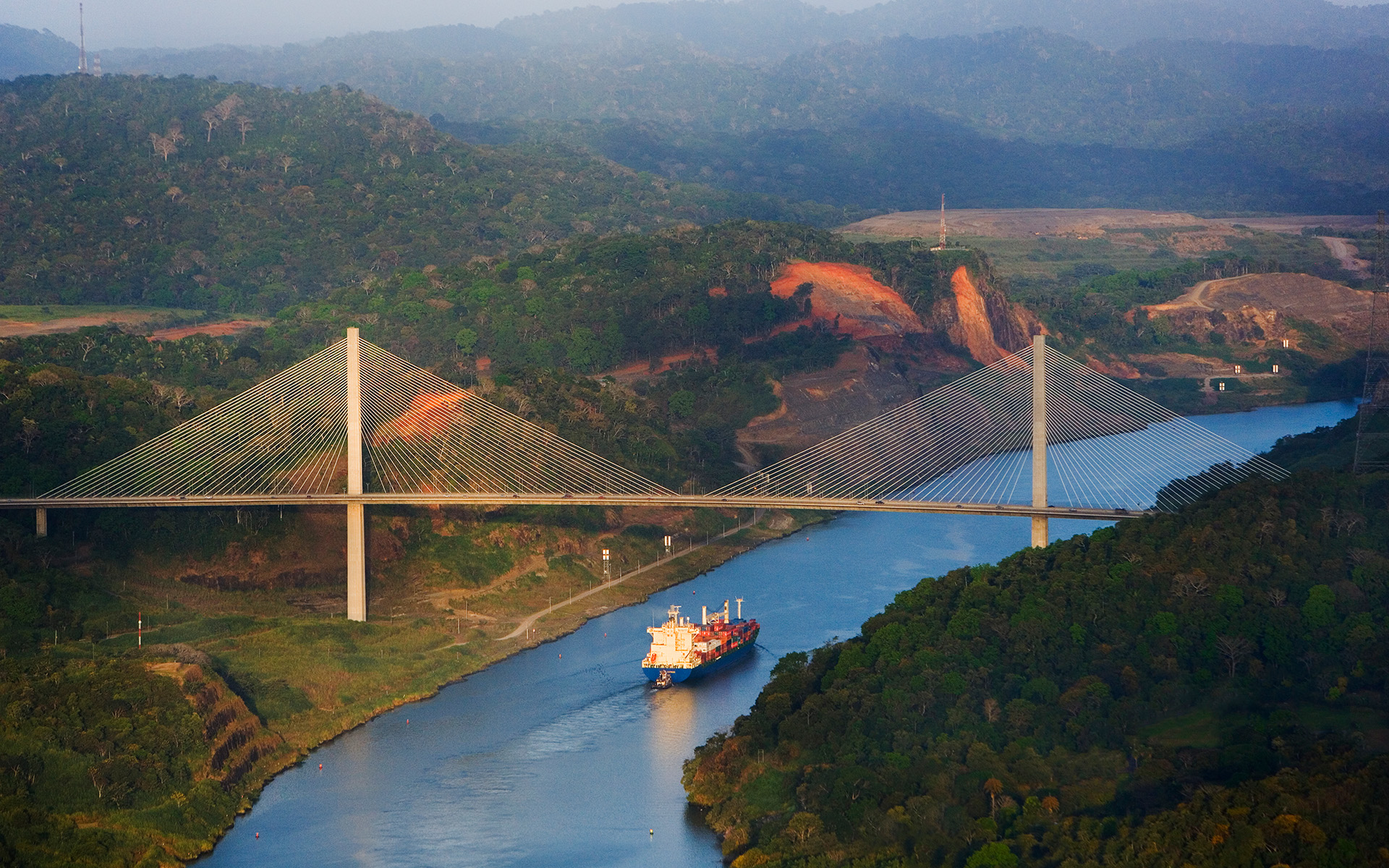 A cargo ship passing under a bridge in Panama City.